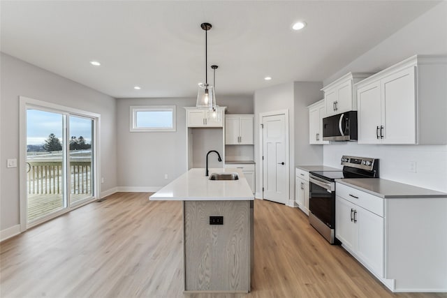 kitchen featuring white cabinetry, sink, hanging light fixtures, a center island with sink, and appliances with stainless steel finishes