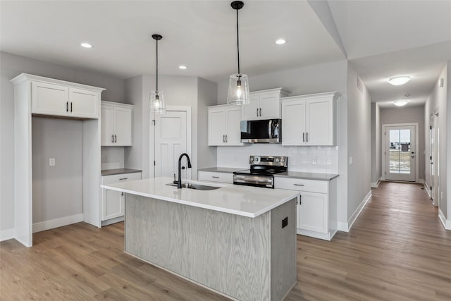 kitchen featuring white cabinets, sink, appliances with stainless steel finishes, and an island with sink