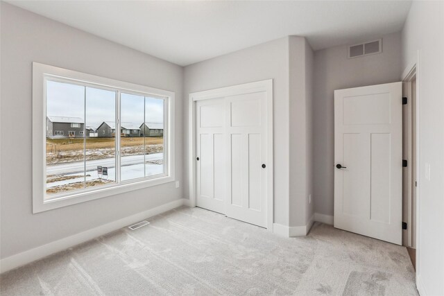 unfurnished bedroom featuring light carpet and a closet