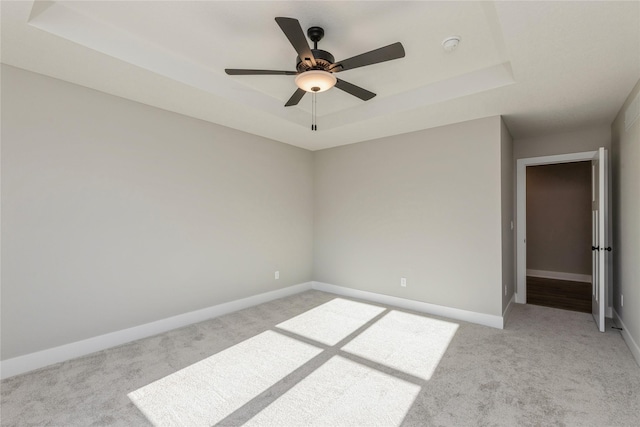 carpeted empty room featuring a raised ceiling and ceiling fan