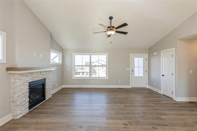 unfurnished living room featuring ceiling fan, a stone fireplace, dark hardwood / wood-style flooring, and vaulted ceiling