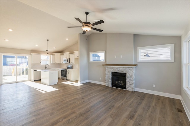 unfurnished living room featuring vaulted ceiling, ceiling fan, sink, a fireplace, and dark hardwood / wood-style floors