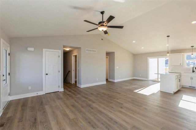 unfurnished living room featuring hardwood / wood-style flooring, vaulted ceiling, ceiling fan, and sink