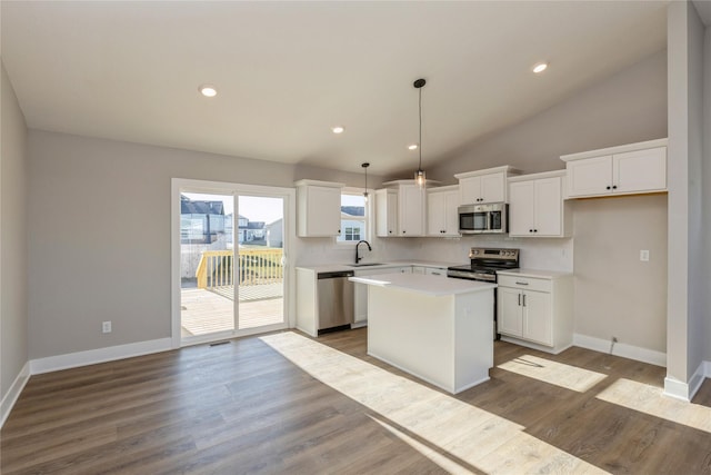 kitchen featuring stainless steel appliances, sink, white cabinetry, a kitchen island, and hanging light fixtures