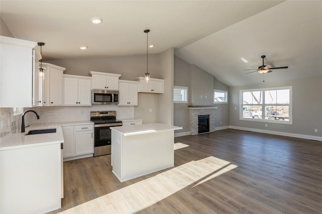 kitchen with stainless steel appliances, sink, decorative light fixtures, a center island, and dark hardwood / wood-style floors