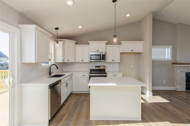 kitchen featuring sink, pendant lighting, lofted ceiling, a kitchen island, and appliances with stainless steel finishes