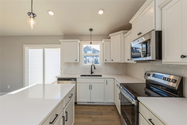 kitchen featuring decorative light fixtures, white cabinetry, sink, and appliances with stainless steel finishes