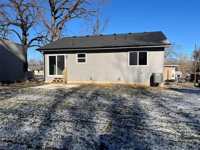 snow covered back of property featuring central AC