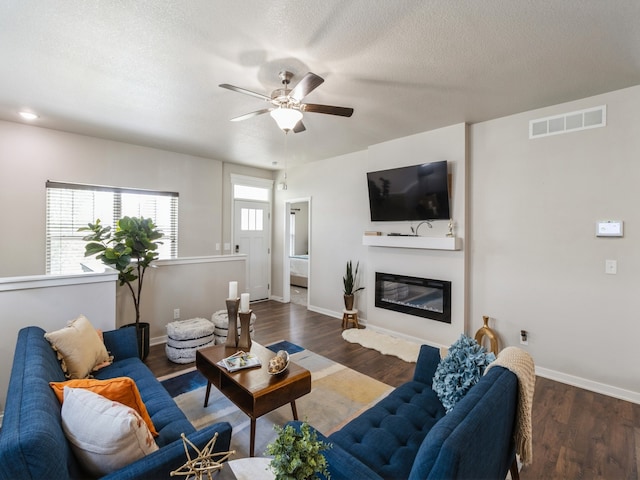 living room featuring dark wood-type flooring, ceiling fan, plenty of natural light, and a textured ceiling