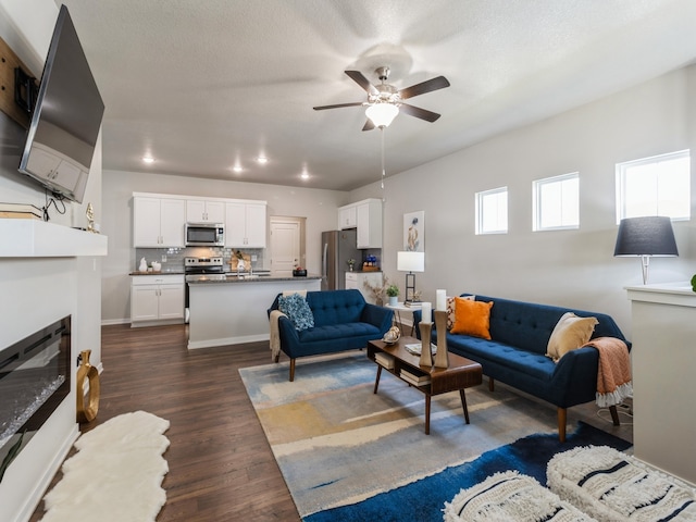 living room featuring a textured ceiling, ceiling fan, and dark hardwood / wood-style flooring