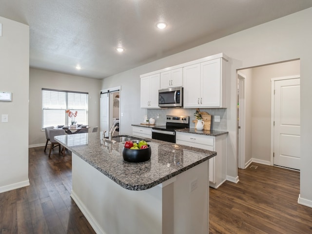 kitchen featuring stainless steel appliances, an island with sink, sink, dark hardwood / wood-style floors, and white cabinets