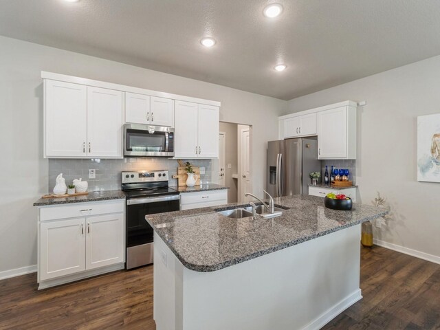 kitchen featuring white cabinets, appliances with stainless steel finishes, sink, dark hardwood / wood-style floors, and a center island with sink