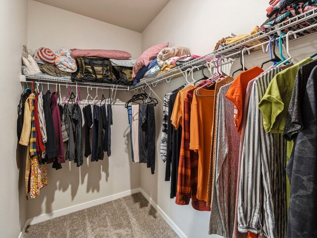 walk in closet with vaulted ceiling and carpet floors