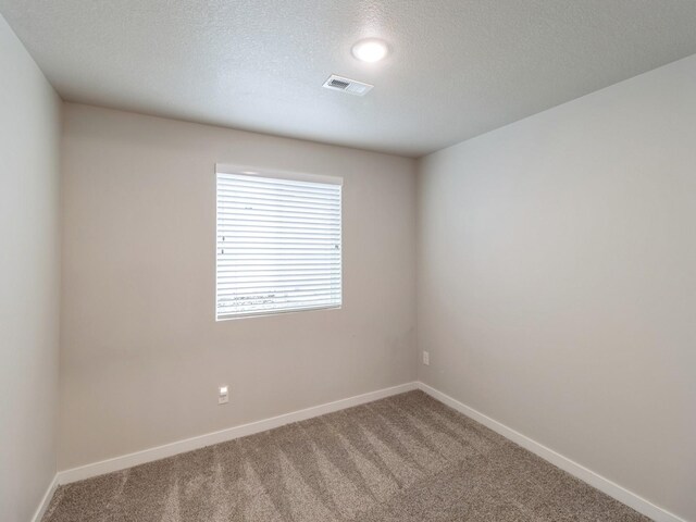 empty room with a textured ceiling and carpet floors