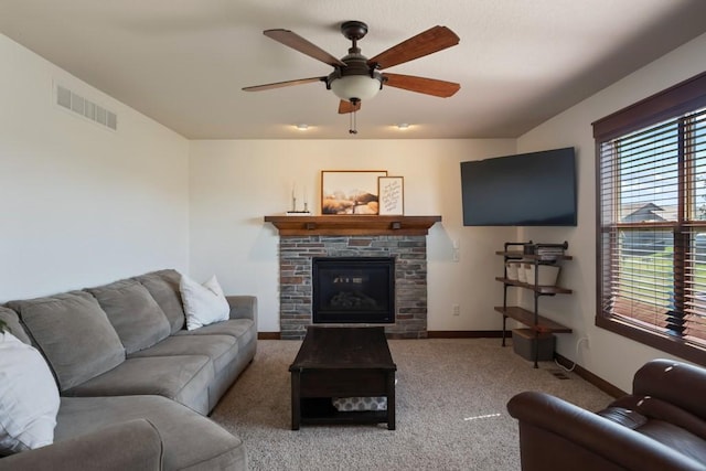 carpeted living room featuring a ceiling fan, a glass covered fireplace, visible vents, and baseboards