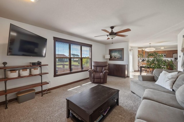 living area with ceiling fan, a textured ceiling, and baseboards