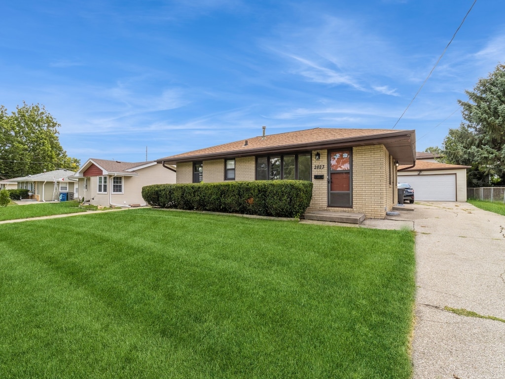 single story home with an outbuilding, a garage, and a front lawn