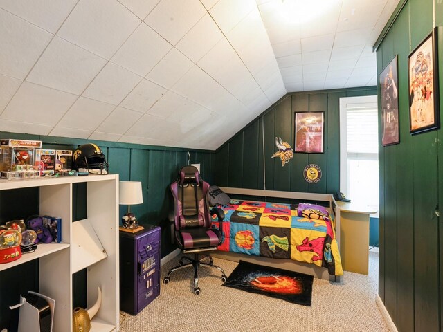 carpeted bedroom featuring lofted ceiling and wood walls