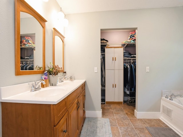 full bathroom featuring double vanity, baseboards, a sink, and a bath