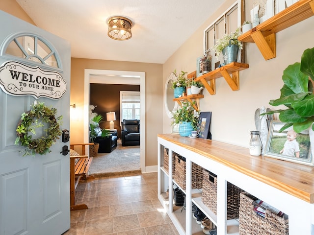 interior space featuring stone finish floor, light colored carpet, and baseboards