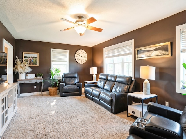 carpeted living area with ceiling fan, a textured ceiling, and baseboards