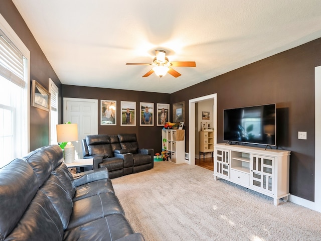 carpeted living room with baseboards and a ceiling fan