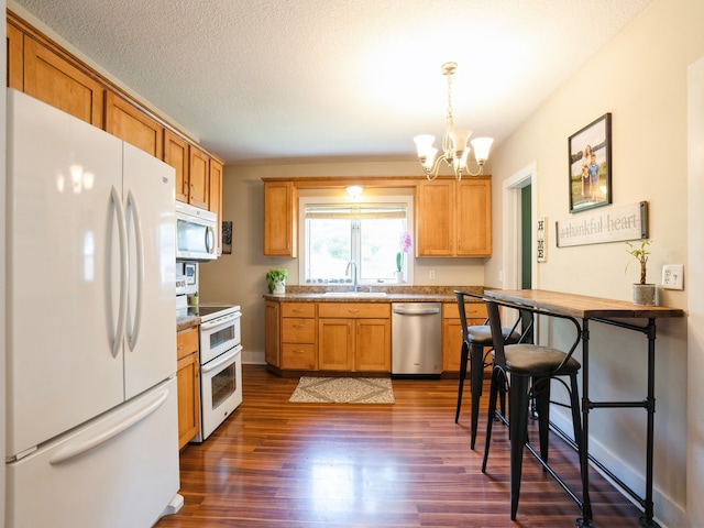 kitchen with pendant lighting, dark wood-type flooring, a textured ceiling, a chandelier, and white appliances