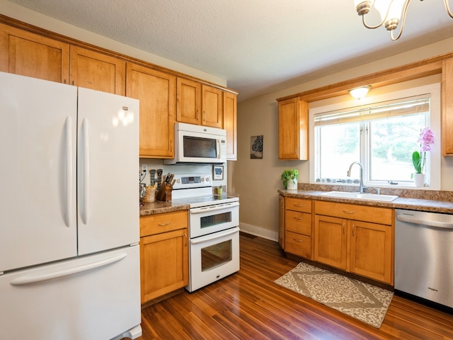 kitchen with white appliances, dark wood-style flooring, a sink, and brown cabinetry