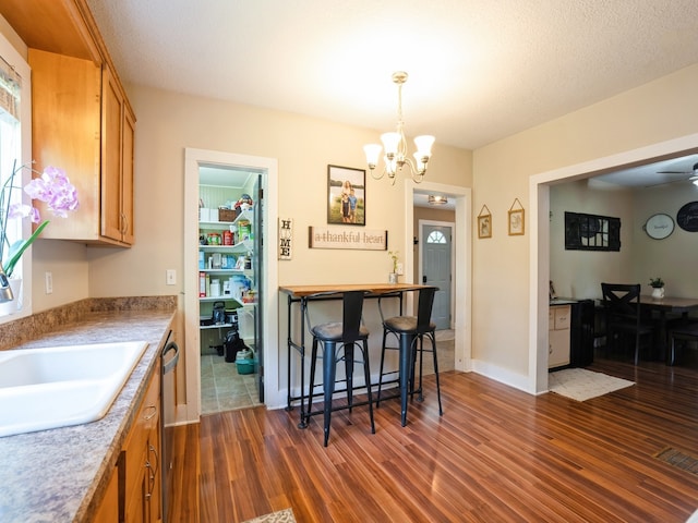 kitchen with dishwasher, dark wood-type flooring, visible vents, and brown cabinets