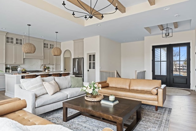 living room with sink, french doors, beamed ceiling, dark hardwood / wood-style floors, and a notable chandelier