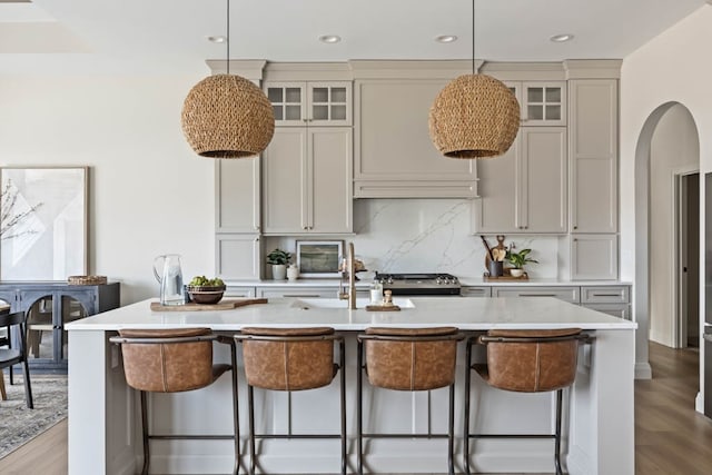 kitchen featuring a breakfast bar, wood-type flooring, and an island with sink