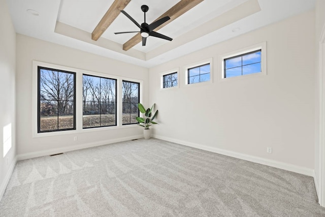 carpeted empty room with beam ceiling, a raised ceiling, and ceiling fan