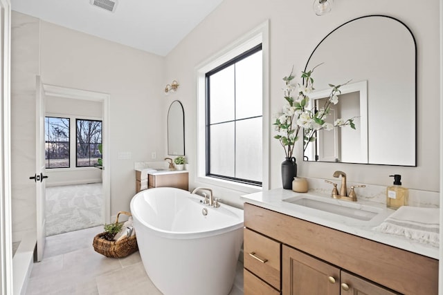 bathroom with a washtub, vanity, tile patterned floors, and plenty of natural light