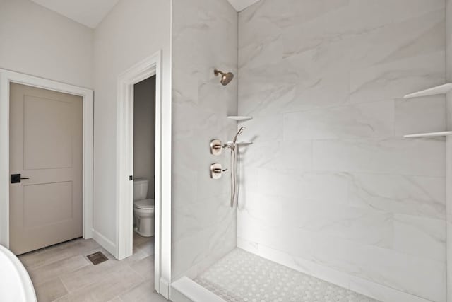 bathroom with tiled shower and toilet