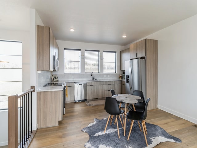 kitchen featuring a sink, light countertops, light wood-type flooring, and stainless steel appliances