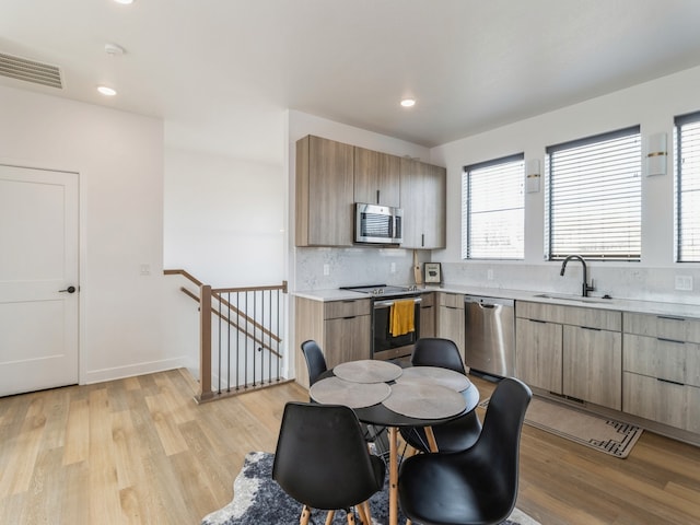 kitchen featuring light wood-style flooring, a sink, stainless steel appliances, light countertops, and modern cabinets