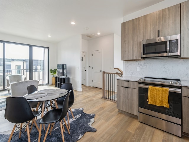 kitchen with modern cabinets, backsplash, light wood-style floors, and appliances with stainless steel finishes