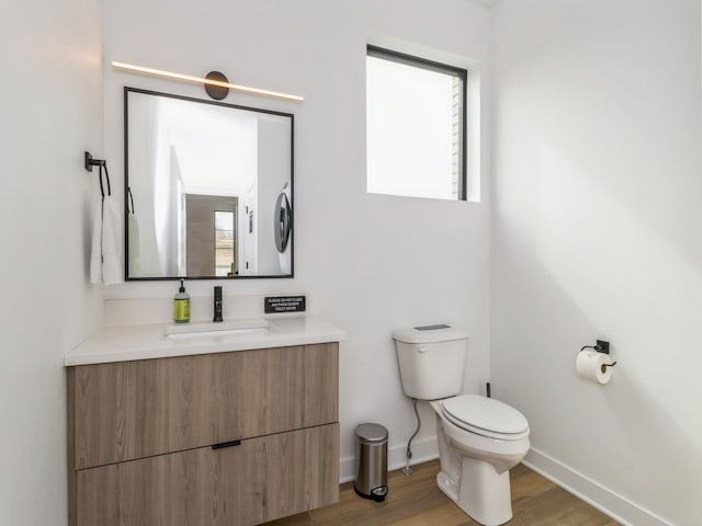 bathroom featuring vanity, toilet, wood finished floors, and baseboards