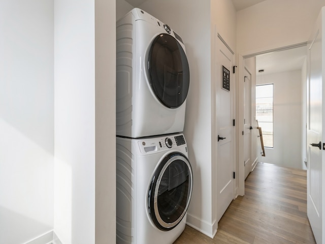 laundry area featuring laundry area, light wood-style floors, and stacked washer and dryer