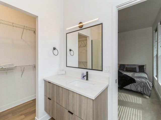 full bath featuring a spacious closet, vanity, and wood finished floors