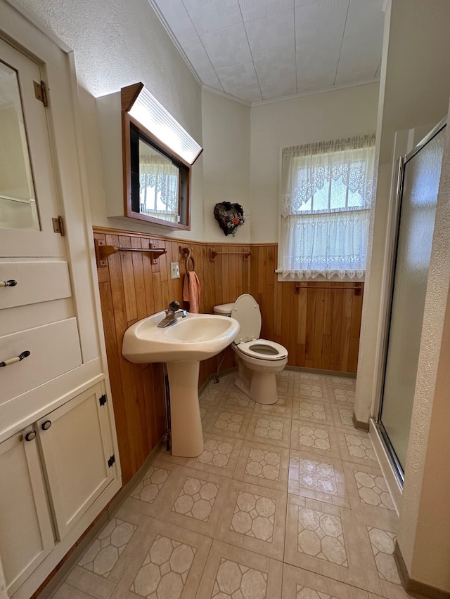 bathroom featuring a wealth of natural light, toilet, wood walls, and an enclosed shower