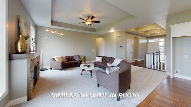 living room with a raised ceiling, hardwood / wood-style floors, and ceiling fan