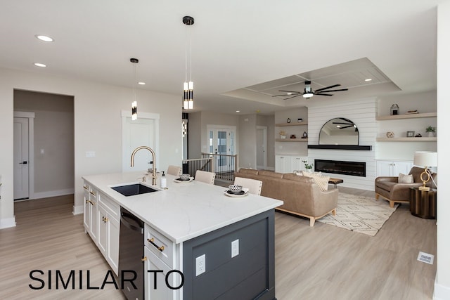 kitchen with white cabinets, hanging light fixtures, a center island with sink, dishwasher, and sink