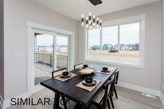 dining area with light hardwood / wood-style floors and a chandelier