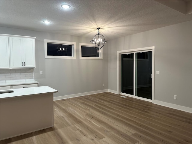 unfurnished dining area featuring hardwood / wood-style floors, a textured ceiling, and an inviting chandelier