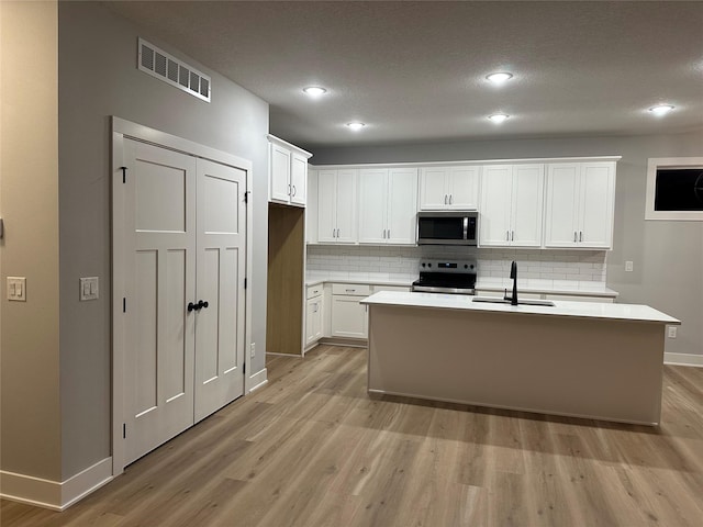 kitchen featuring a kitchen island with sink, white cabinets, sink, tasteful backsplash, and stainless steel appliances