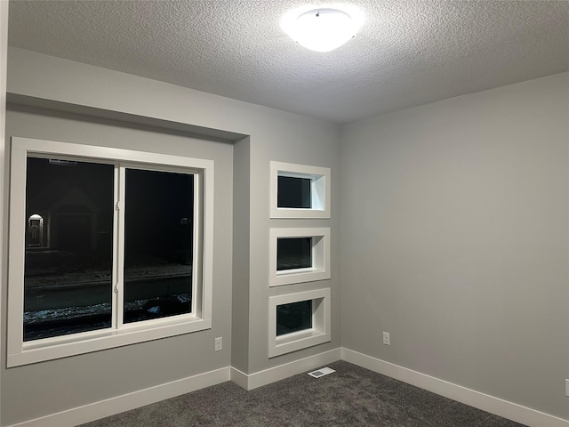 unfurnished living room with dark carpet and a textured ceiling