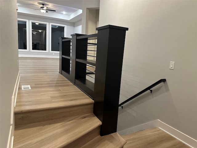 stairway featuring ceiling fan and wood-type flooring