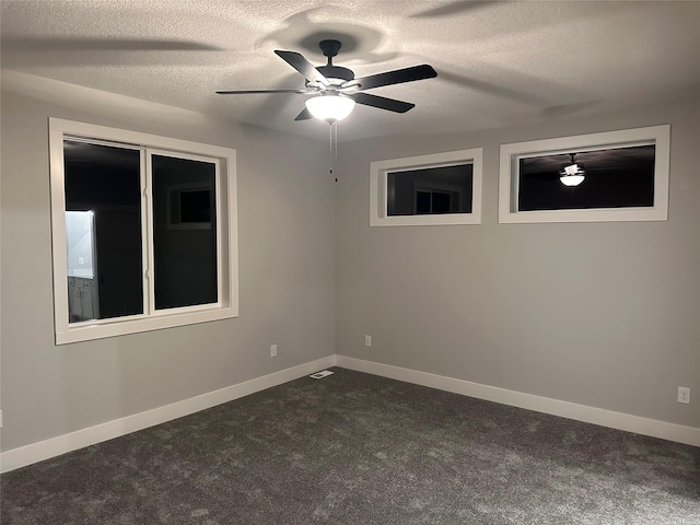 empty room with ceiling fan, dark carpet, and a textured ceiling