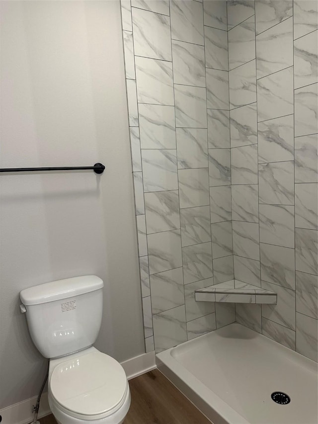 bathroom featuring hardwood / wood-style flooring, toilet, and a shower